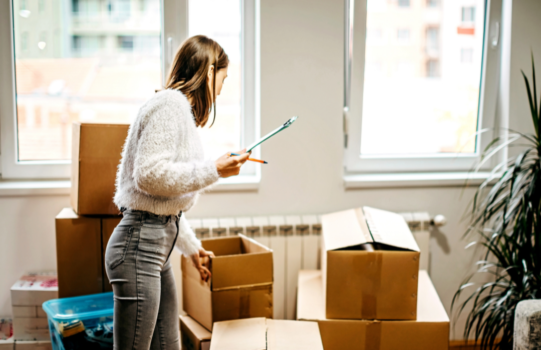 A woman holding a checklist surrounded by boxes.