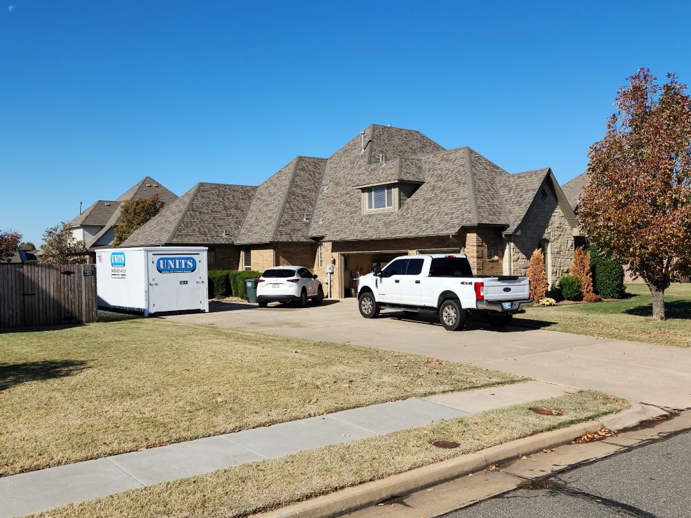 A Units of Oklahoma City container sitting in the driveway of a house.