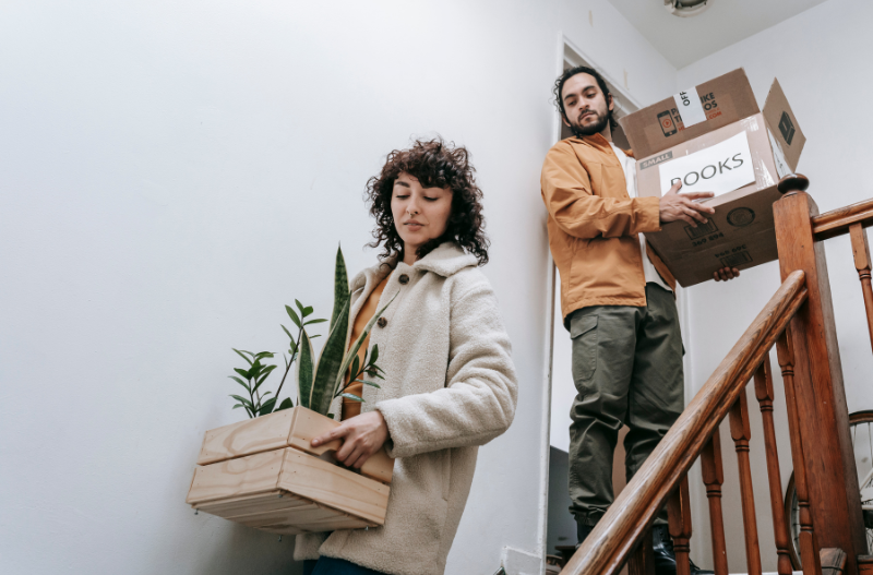 A couple moving boxes out of their apartment.