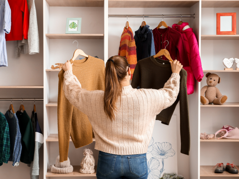 A woman choosing between two different shirts to wear.