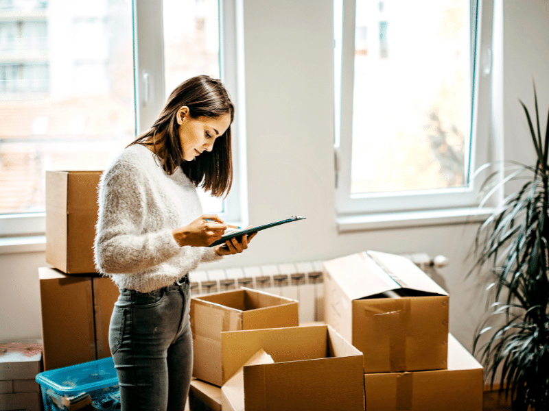 A woman looking at a checklist surrounded by boxes.