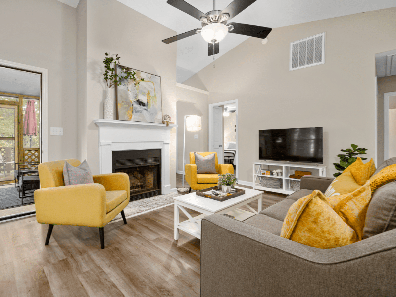 A living room that is clean and decorated with yellow chairs.