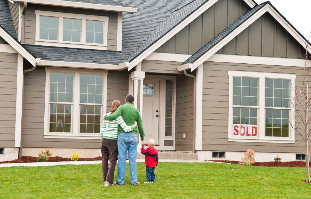 Units of Omaha & Lincoln family standing in front of house after buying it