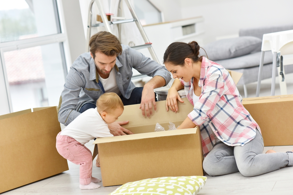 Mom and Dad open a box with their baby.