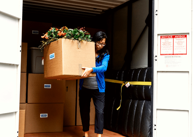 Woman carrying a large box out of her portable storage container.