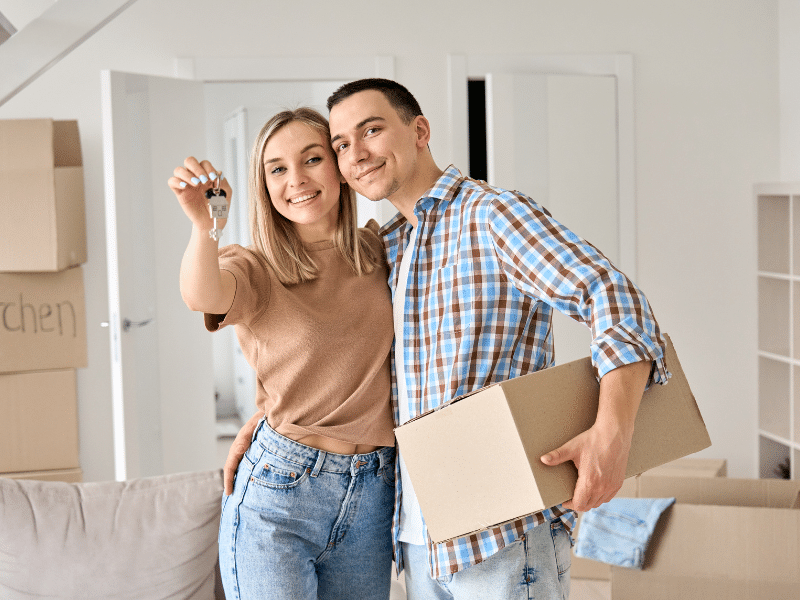 Happy couple holding up keys in their new house.