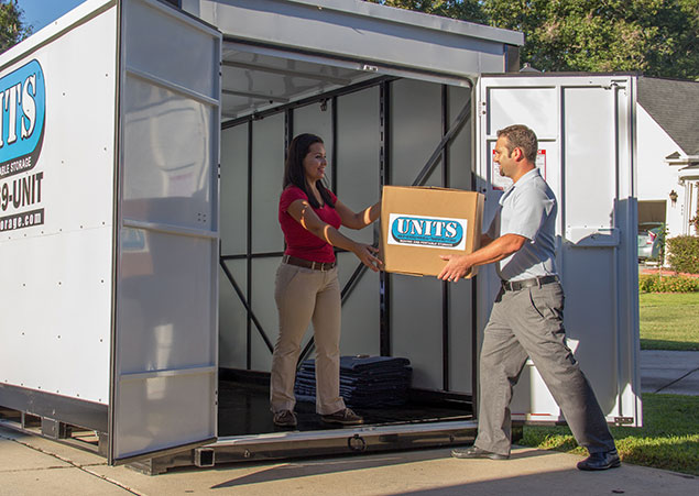 Man helps woman move carboard boxes into a UNITS Moving and Portable Storage of Phoenix container.