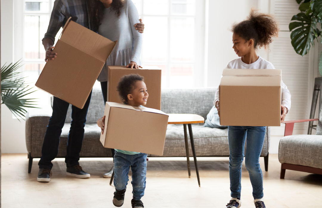 Kids helping their parents move cardboard boxes while their parents look on from background.