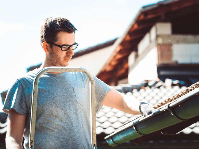 Man in glasses wearing gloves preparing for work.