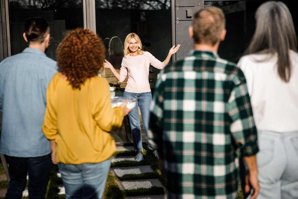 Woman greets her friends to her house.