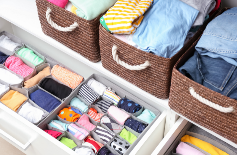 Closet with baskets and drawers filled with clothes.