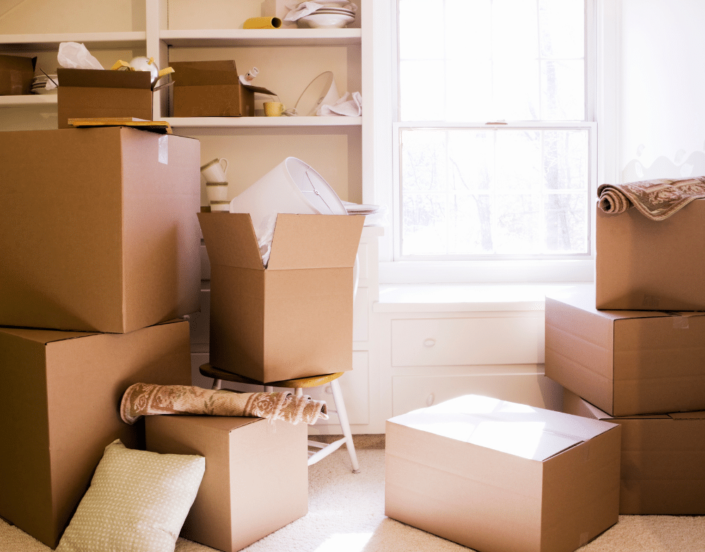 Cardboard boxes sitting next to a window in a living room.