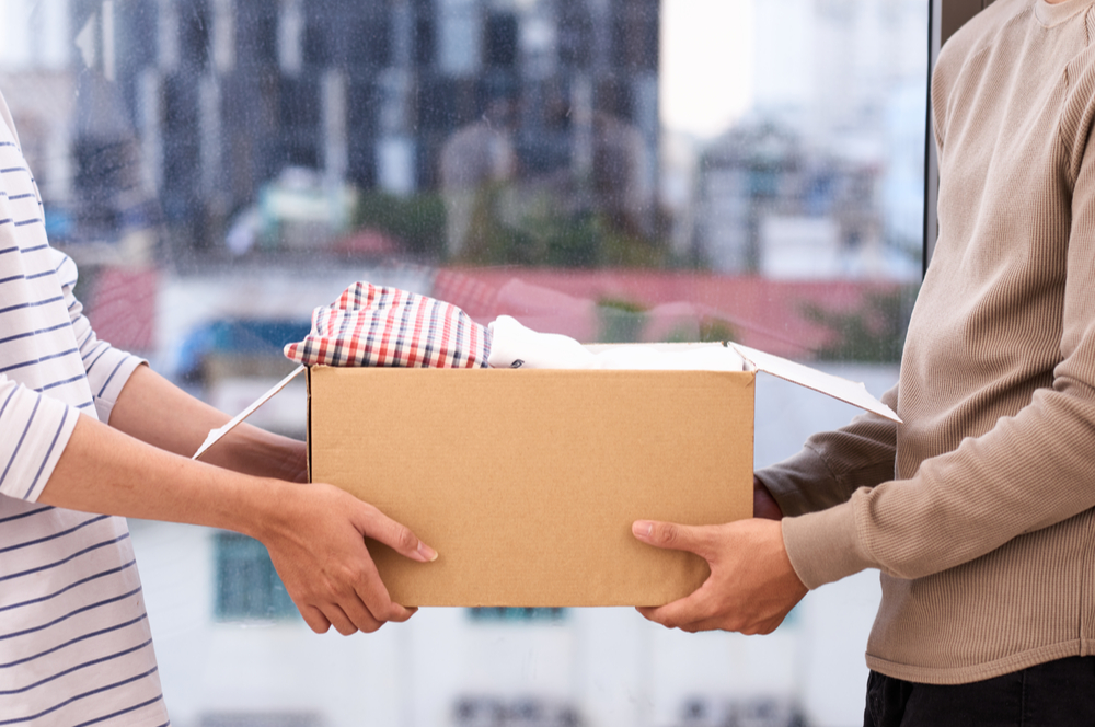 Man handing off a small cardboard box to someone else.