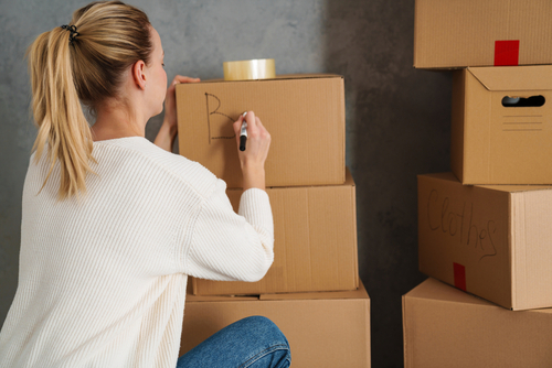 Woman labeling cardboard boxes.