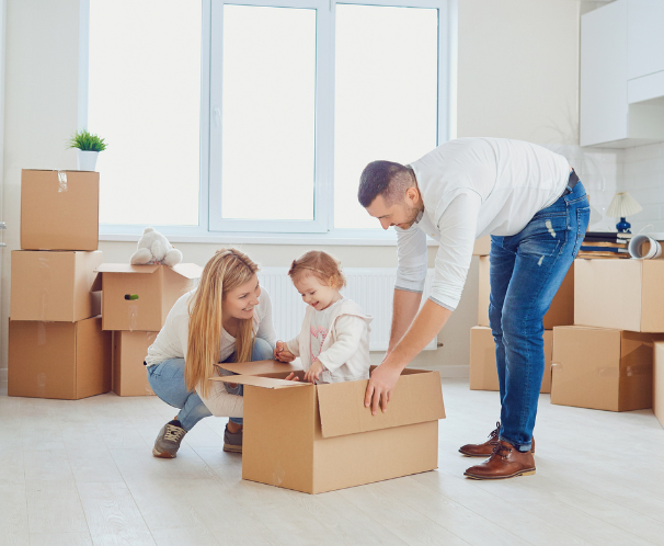 Man and woman playing with their baby in a cardboard box.