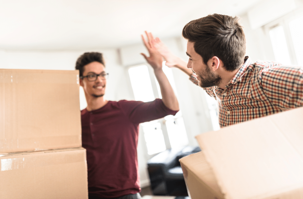 Two guys high five after moving in to their new home.