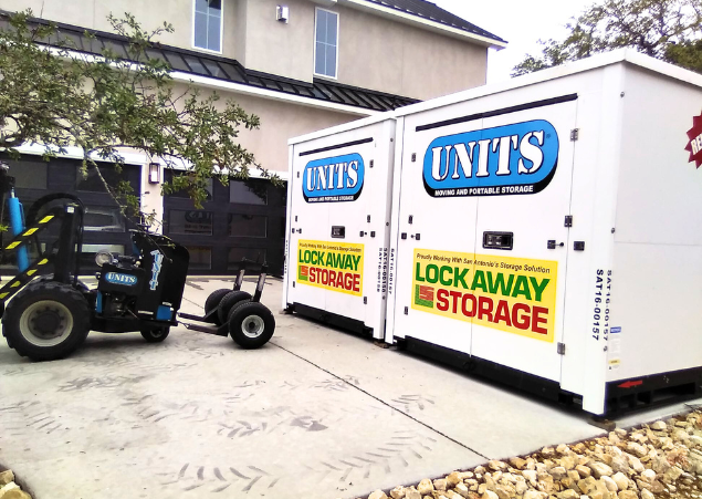 Two UNITS of San Antonio portable storage containers and the ROBO-UNIT delivery system parked on a driveway.