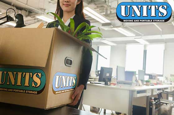 Woman packing a box with the units logo full of office supplies.