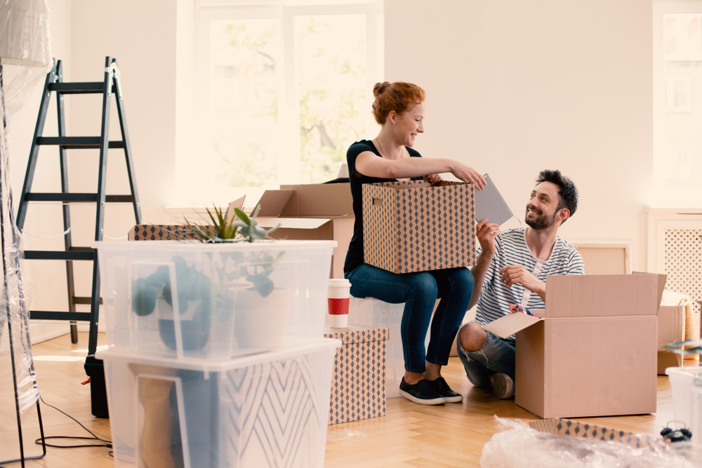 A couple packing their belongings into boxes in their home.