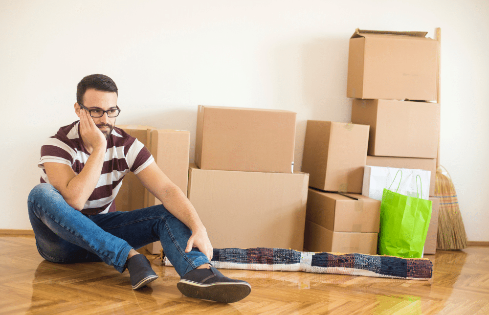 Man sitting on the ground surrounded by boxes.