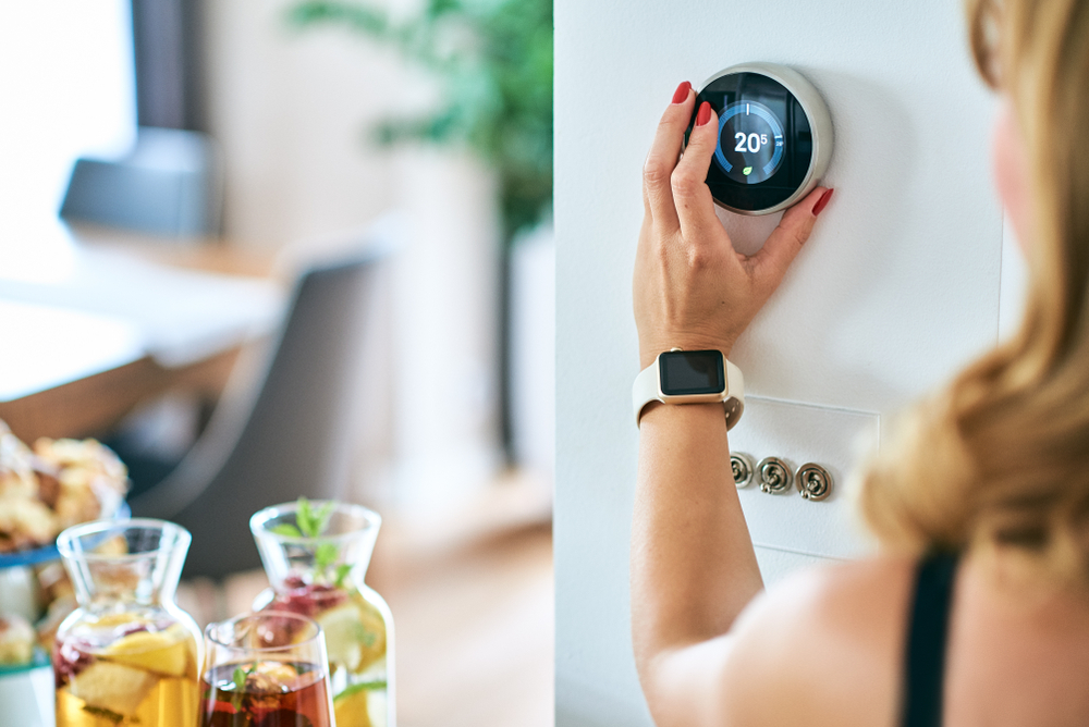 Woman changing the temperature on the thermostat.