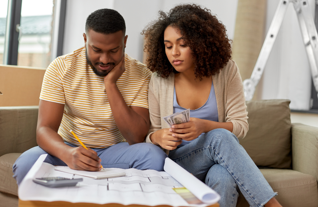 Couple looking at floors plans of a house and taking notes.