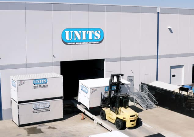 Outside of our Portable Storage facility with two portable storage containers stacked ontop one each other, and one being transported with a fork lift.